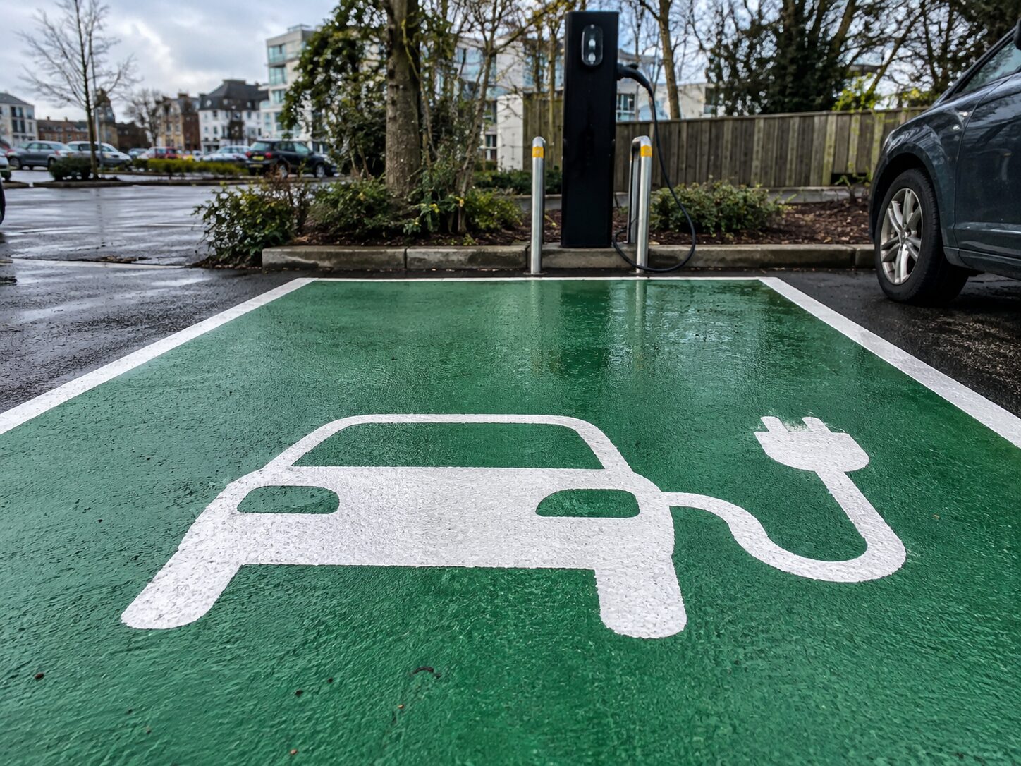 White electric vehicle symbol on a green charging bay